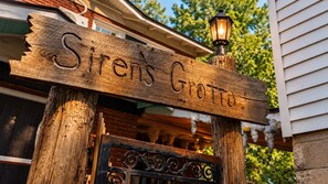 En träskylt med texten ”Sirens Grotta” monterad på en stolpe, med en lykta ovanför.
