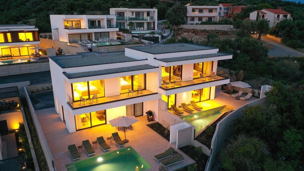 Ein modernes mehrstöckiges Haus mit Schwimmbad, Außenbereich und einem gut beleuchteten Balkon.