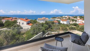 Ein Balkon mit Blick auf das Meer, Häuser und einen Swimmingpool.