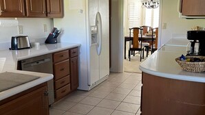 A kitchen with wooden cabinets, a white refrigerator, a toaster, and a coffee maker on the counter. - Your Private 19th Hole With Golf Cart Included In Rental (Sun City West)
