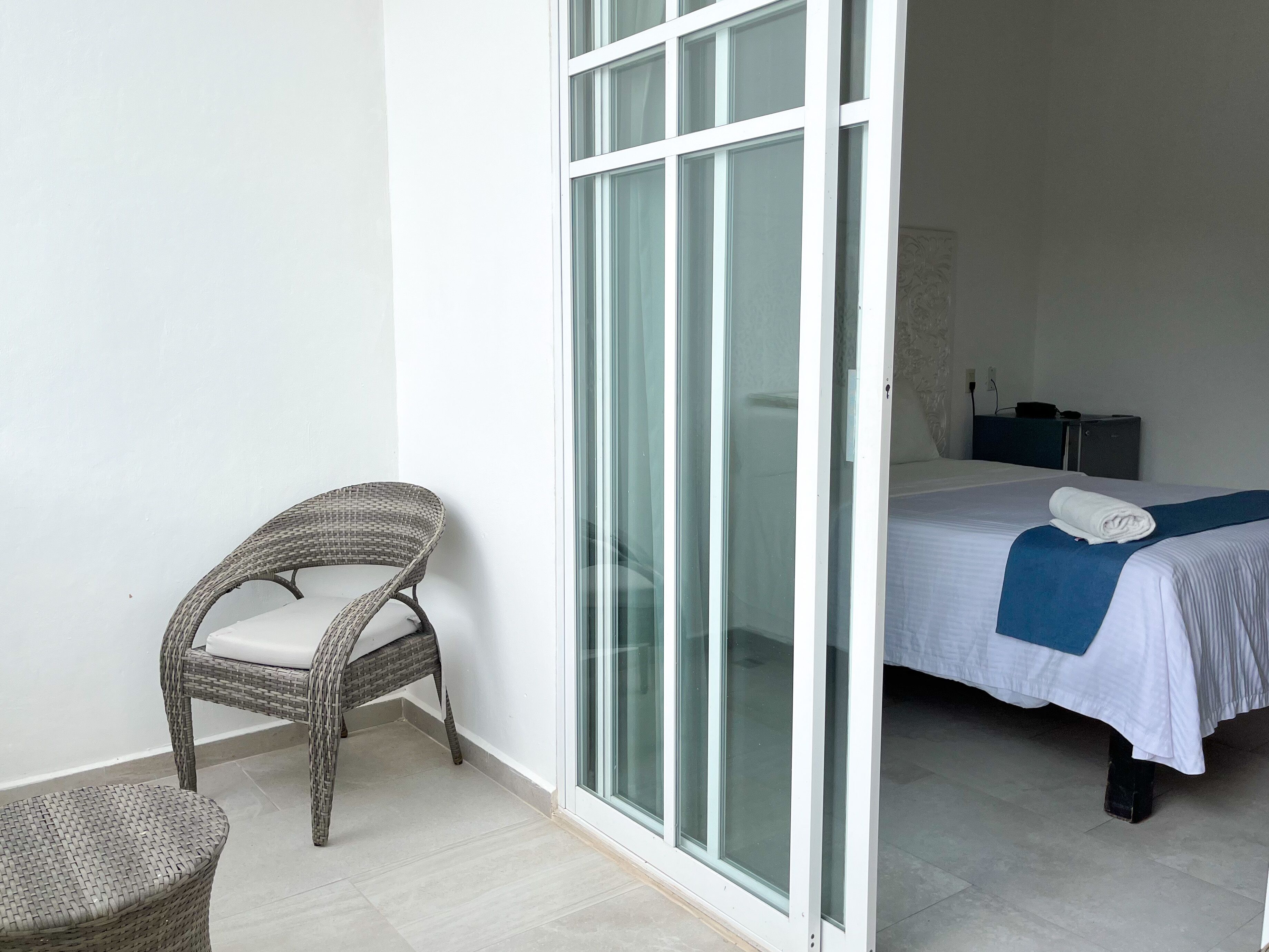 Una habitación con una cama, una silla y un ventanal corredero que da a un baño.