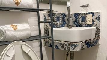Un baño con inodoro, lavamanos y toallero con toallas.