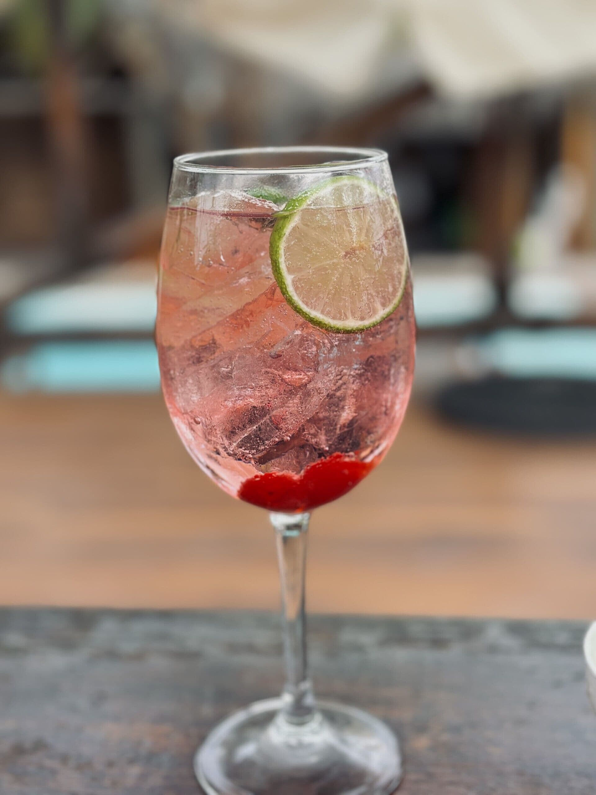 Un vaso de bebida con cubitos de hielo y una rodaja de lima sobre una mesa.