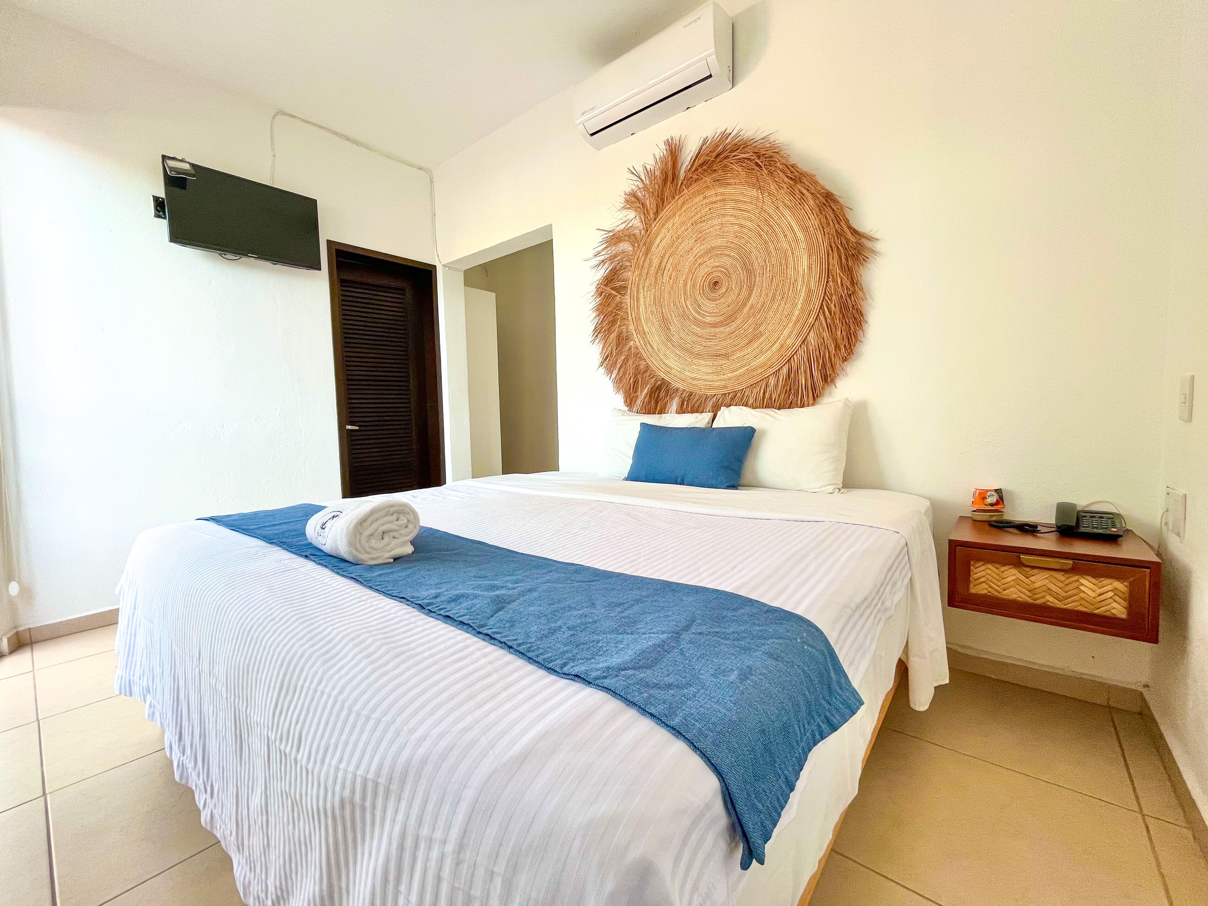 A hotel room with a bed, a nightstand, a wall-mounted TV, and a door.