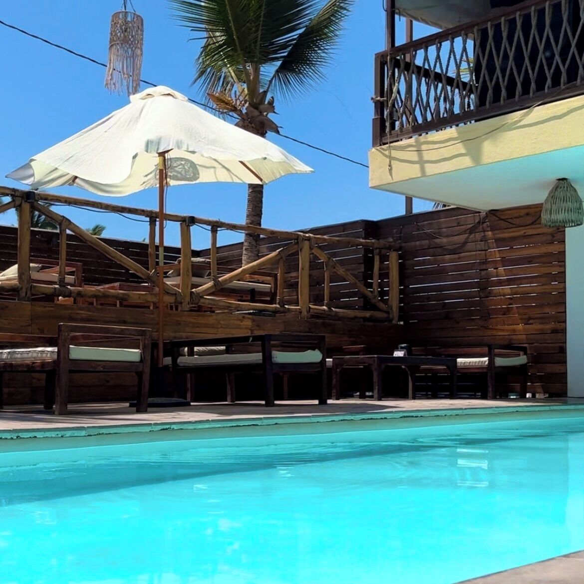 Ein Poolbereich mit Holzkonstruktionen und einem weißen Sonnenschirm.