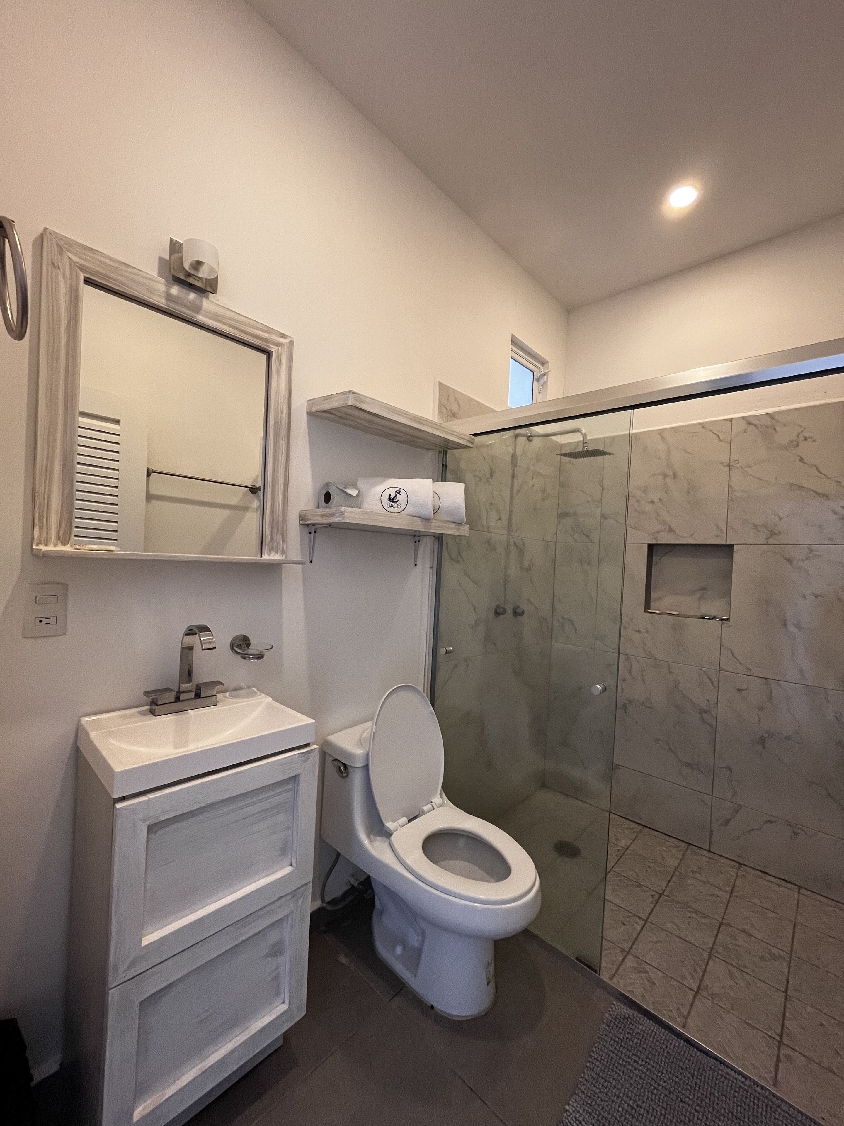 A modern bathroom with a toilet, sink, and shower.