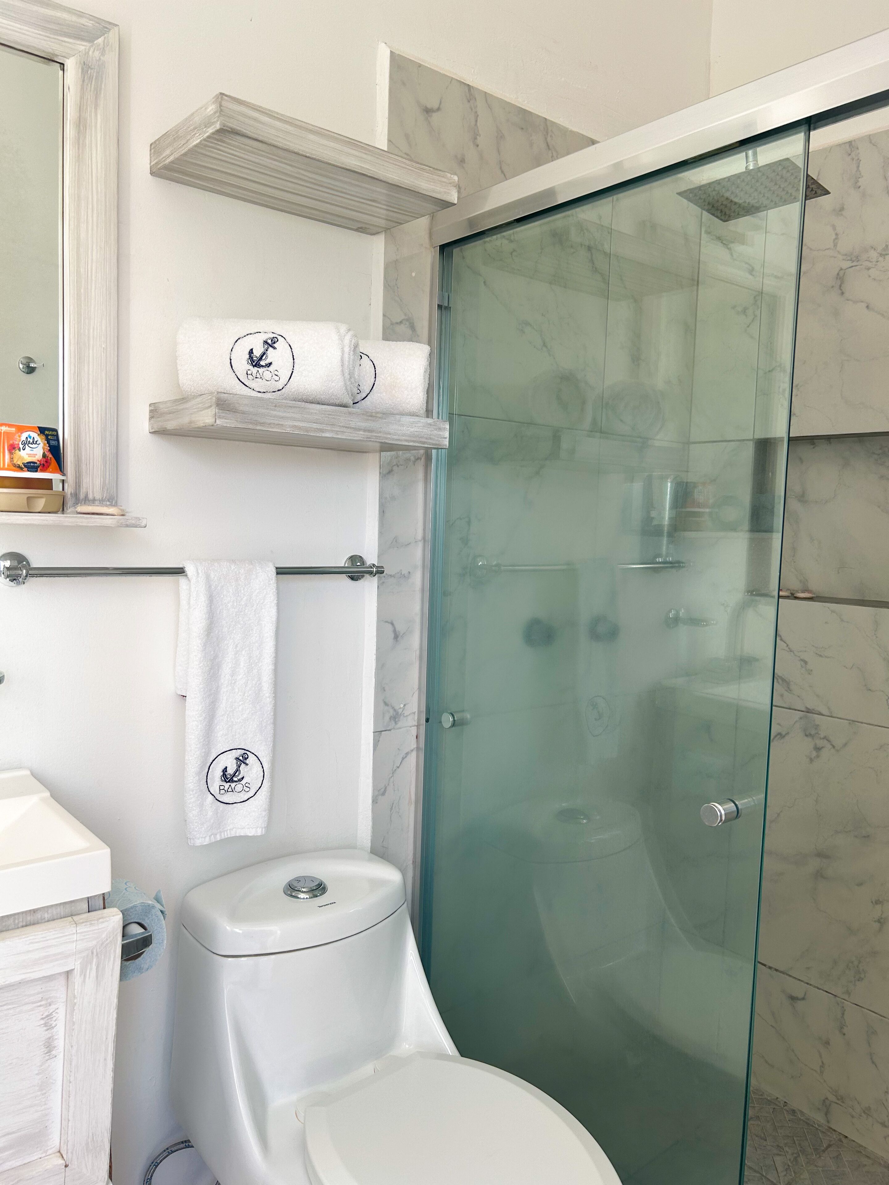 A modern bathroom with a glass-enclosed shower, a toilet, and a sink.