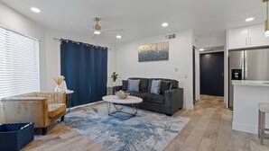 Ein modernes Wohnzimmer mit einem grauen Sofa, einem runden Couchtisch und einem blauen Teppich.