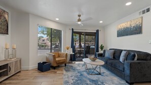 Ein modernes Wohnzimmer mit einem grauen Sofa, einem runden Couchtisch und einem blauen Teppich mit Muster.