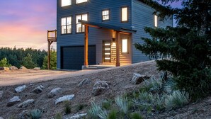 A modern two-story house with a garage, large windows, and a covered porch. - Mountain & Pond Views, Hot Tub, Stargazing, Kid + Dog Friendly, Loft+3BR (Florissant)