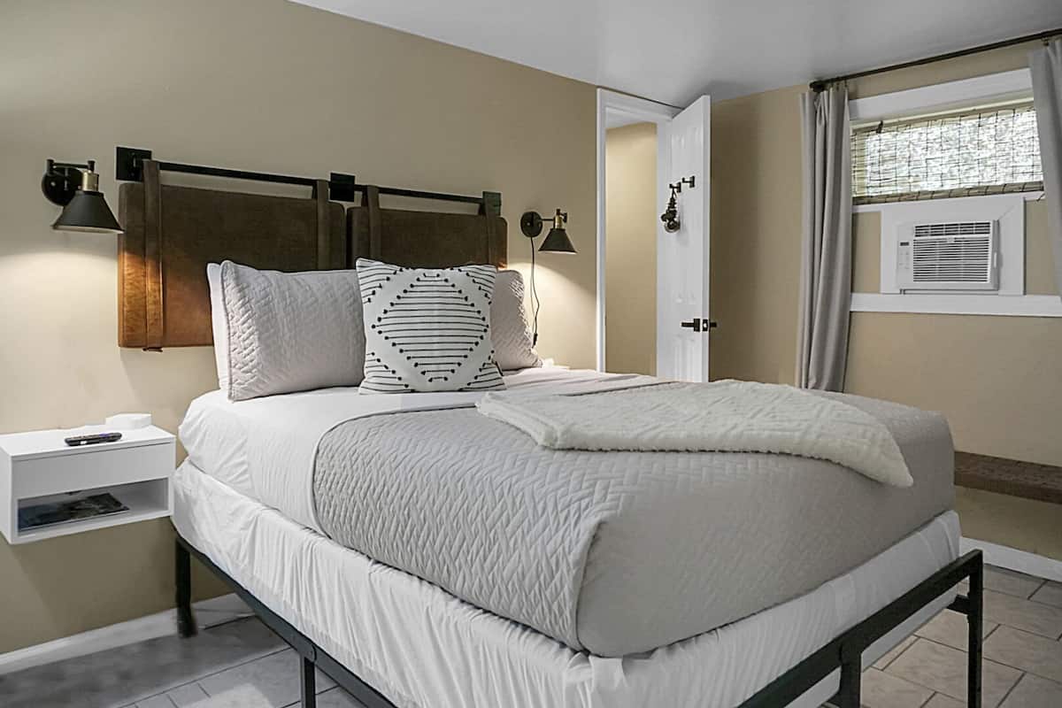 Ein ordentlich eingerichtetes Schlafzimmer mit einem Bett, Nachttischen und einem Fenster mit Vorhängen.
