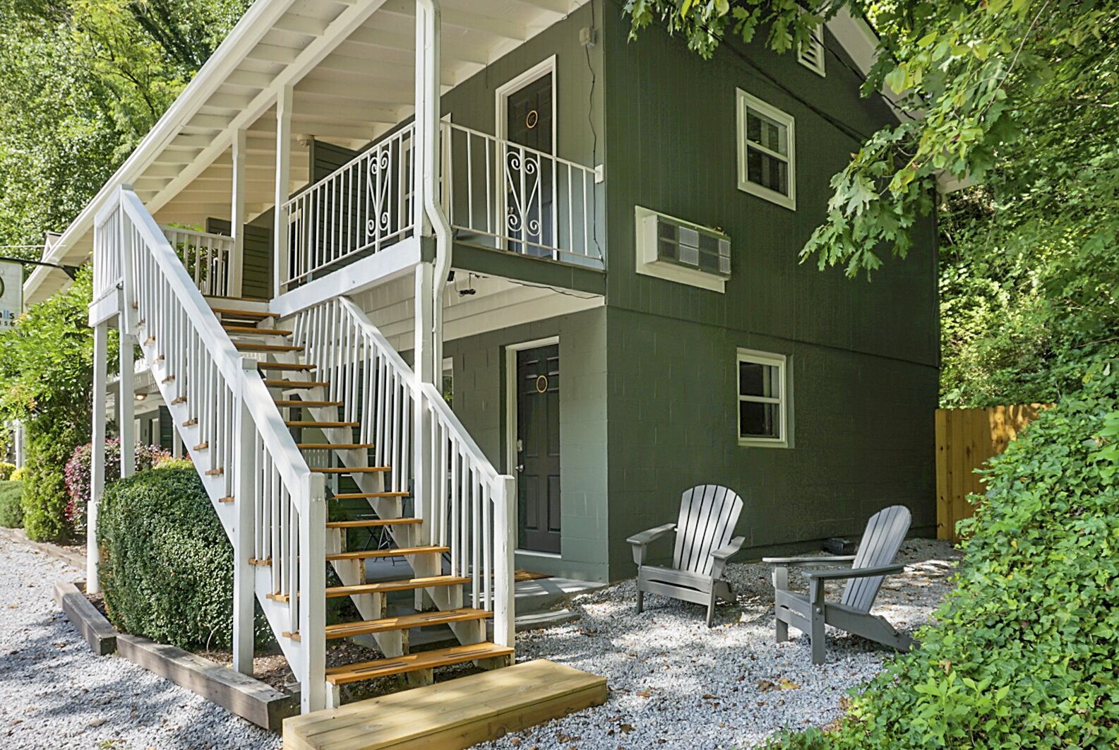 A two-story house with a covered porch, a staircase, and outdoor seating.