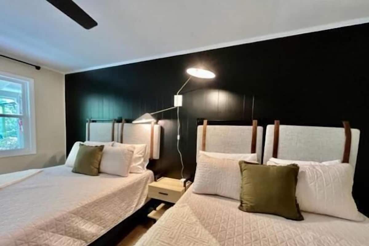 Ein modernes Hotelzimmer mit zwei Betten, einem großen Fenster und einem Deckenventilator.