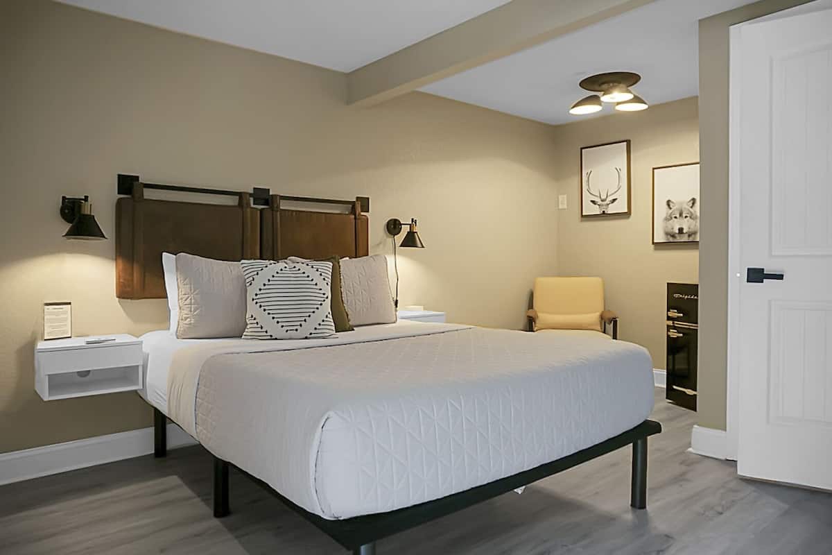 Ein Schlafzimmer mit Bett, Nachttischen, einem Sessel, einem Kleiderschrank und Wandleuchten.