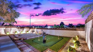Ein Golfplatz bei Nacht mit einem gepflegten Putting Green, einer Golftasche und klarem Himmel.