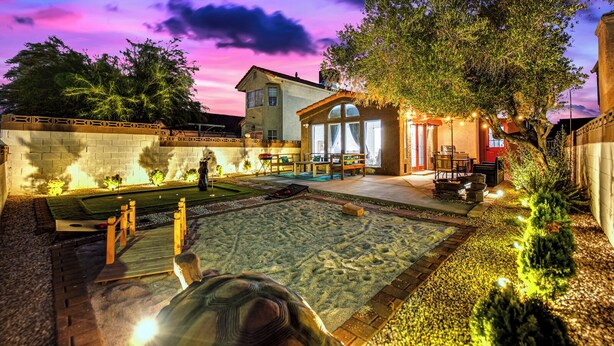 Ein gut beleuchteter Hinterhof mit Pool, Grillplatz und Terrasse mit Gartenmöbeln.