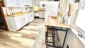 A modern kitchen with white cabinets, a wooden countertop, and a patterned rug. - Walking distance to Betsie River & 10 minutes to Lake Michigan & Crystal Mnt! (Benzonia)