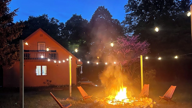 A backyard with a fire pit, string lights, and two chairs. - Walking distance to Betsie River & 10 minutes to Lake Michigan & Crystal Mnt! (Benzonia)