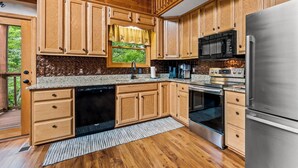A kitchen with wooden cabinets, a stainless steel refrigerator, a dishwasher, a stove, and a microwave. - Mountain Vacation Time! 2 miles to GSMNP@ Line Springs~Hot Tub~Games~2 Decks (Sevierville)