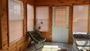 A wooden cabin interior with a door, a chair, and a couch.