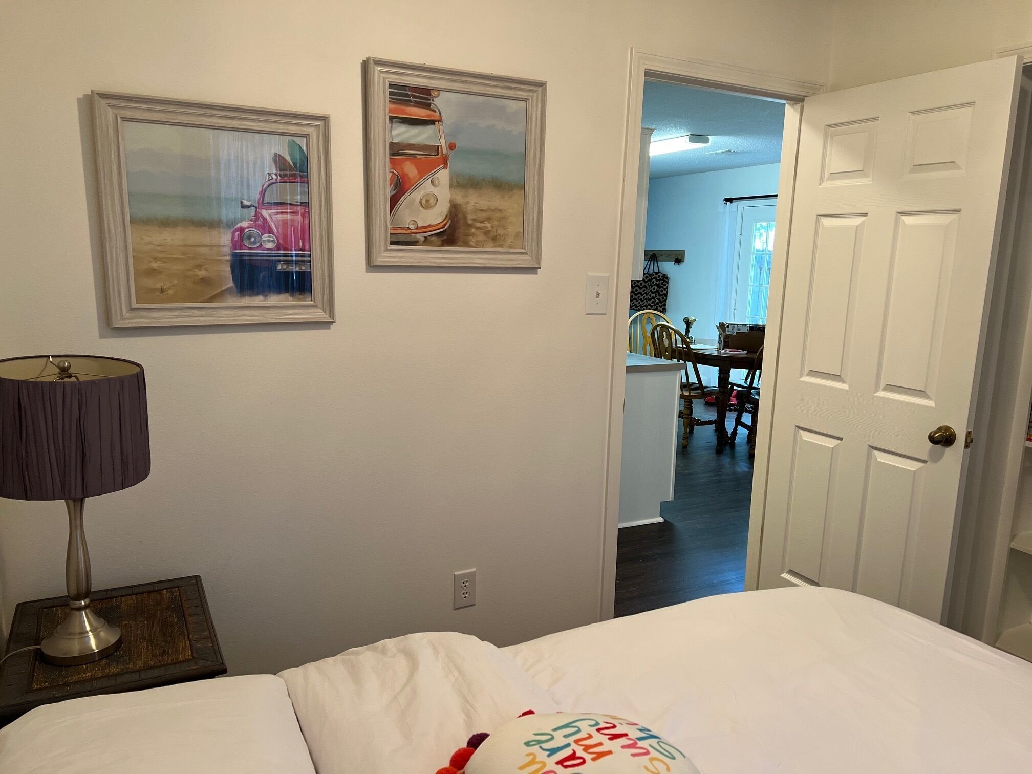 Ein Schlafzimmer mit einem Bett, einer Lampe und zwei gerahmten Bildern an der Wand.