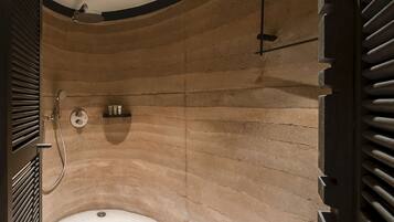 Un baño moderno con una zona de ducha curva, un estante empotrado con artículos de aseo y desagüe visible.