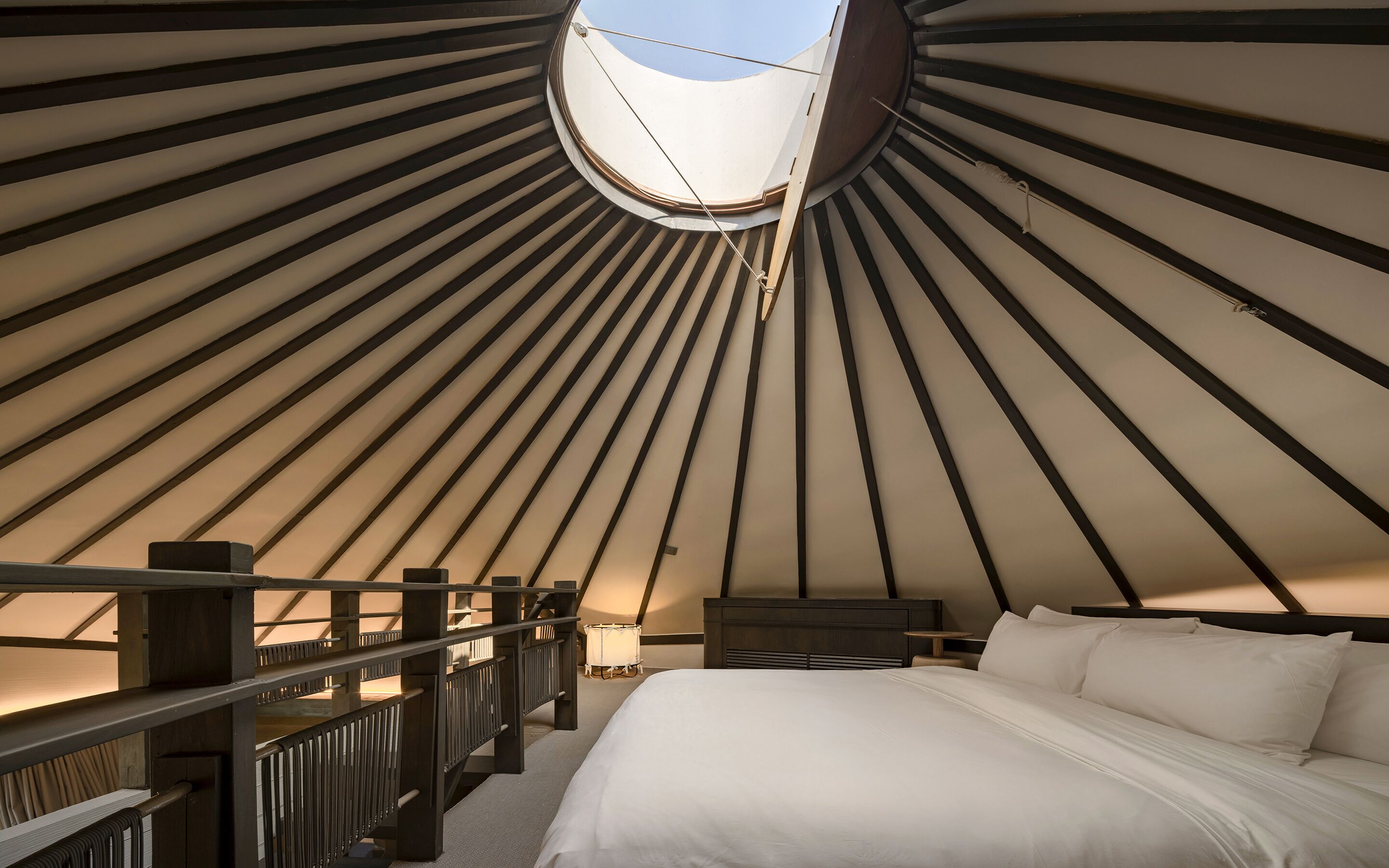 A room with a bed, a nightstand, and a wooden railing.