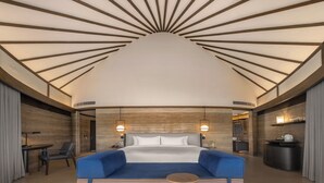 Una habitación de hotel moderna con una cama grande, un sofá azul y una mesa redonda de madera.