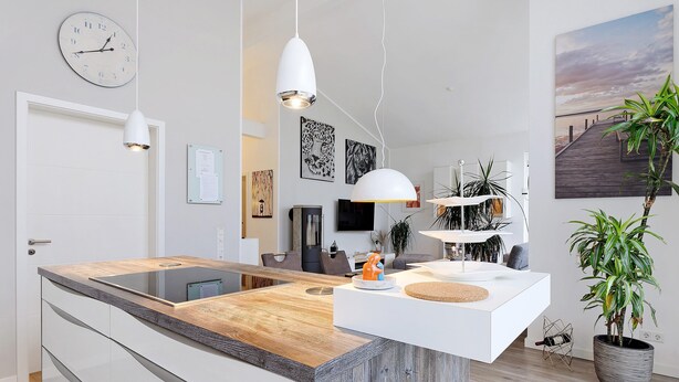 A modern kitchen with a wooden countertop, white cabinetry, pendant lighting, and a large potted plant. - Idyllic Holiday Home with Private Terrace and Wi-Fi (Edewecht)