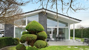 A modern house with a patio, a car, and neatly trimmed bushes. - Idyllic Holiday Home with Private Terrace and Wi-Fi (Edewecht)