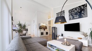 A modern living room with grey sofas, a white coffee table, and a flat-screen TV mounted on the wall. - Idyllic Holiday Home with Private Terrace and Wi-Fi (Edewecht)