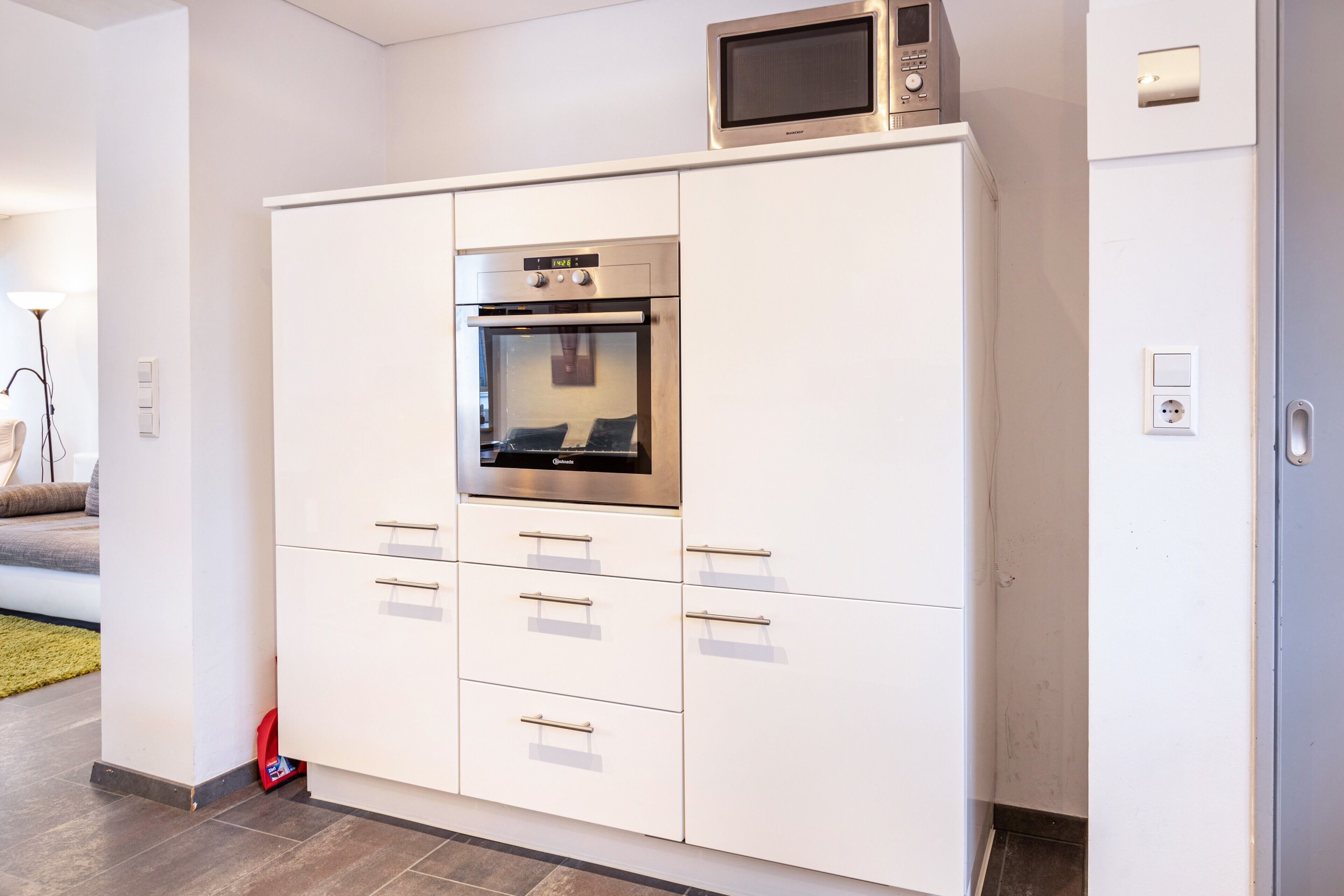 A kitchen with a built-in oven, microwave, and a cabinet with drawers.