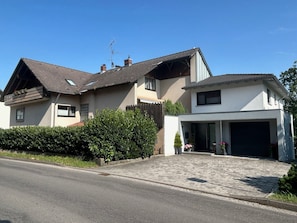 A two-story house with a garage, a sloped roof, and a well-maintained garden. - Ferienwohnung Kalter Wangen (Hohentengen a.H.)