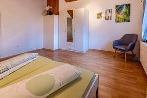 A bedroom with a bed, a chair, a wardrobe, and a door leading to a closet. - Ferienwohnung Kalter Wangen (Hohentengen a.H.)