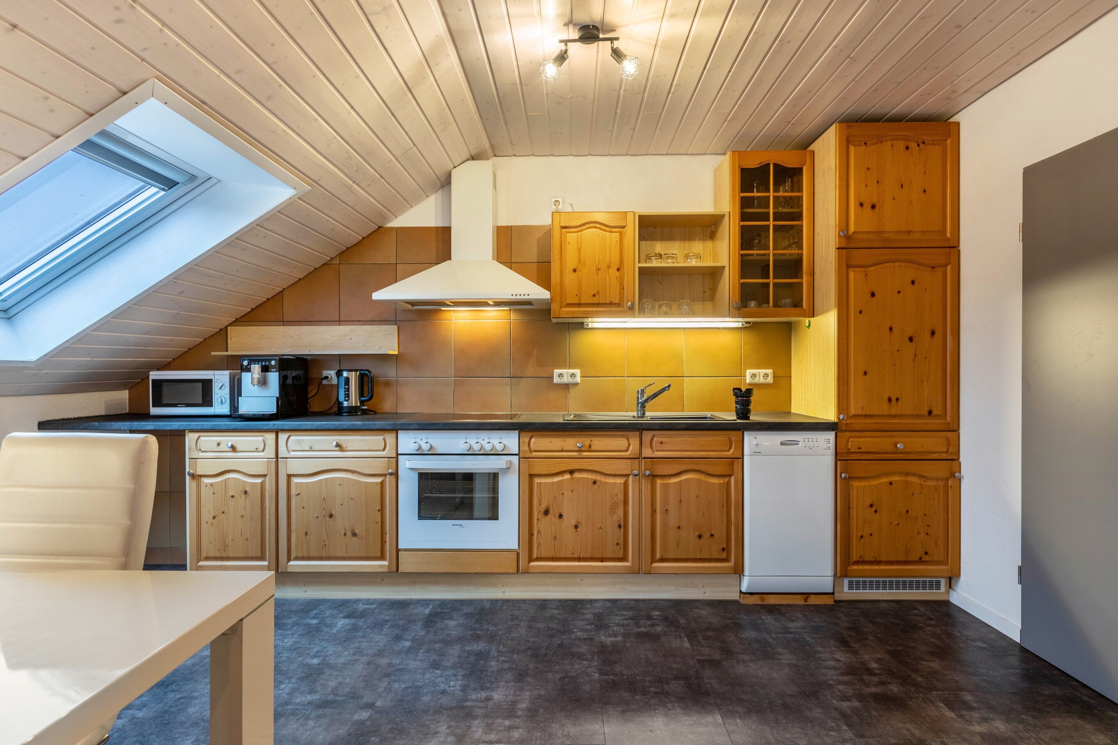 Une cuisine dotée de meubles en bois, d’un four à micro-ondes, d’une cuisinière et d’un lave-vaisselle.