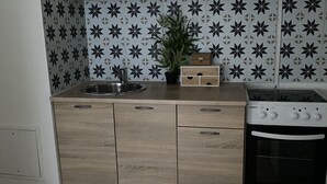 Une cuisine avec des meubles de couleur bois clair, un crédence à motifs noir et blanc, une cuisinière et un évier.