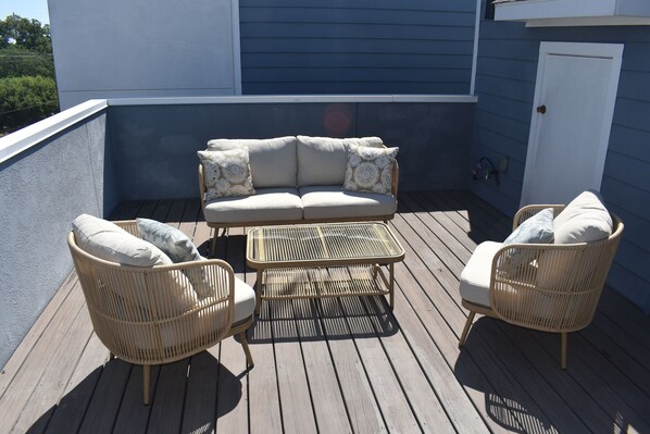 Relax on the balcony with a sofa and armchairs, surrounded by patterned cushions.