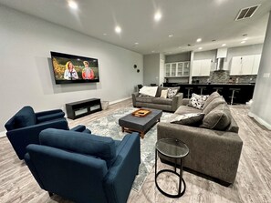 Relax in this stylish living room with a flat-screen TV, comfortable seating area, and kitchenette.