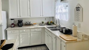 A kitchen with white cabinets, a coffee maker, a sink, and a wall-mounted sign. - mounting view and popular for hiking area (Desert Hot Springs)