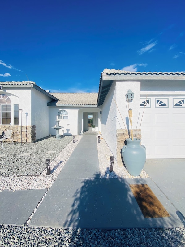 A residential property with a paved driveway leading to a garage, a stone pathway, and a decorative light fixture.