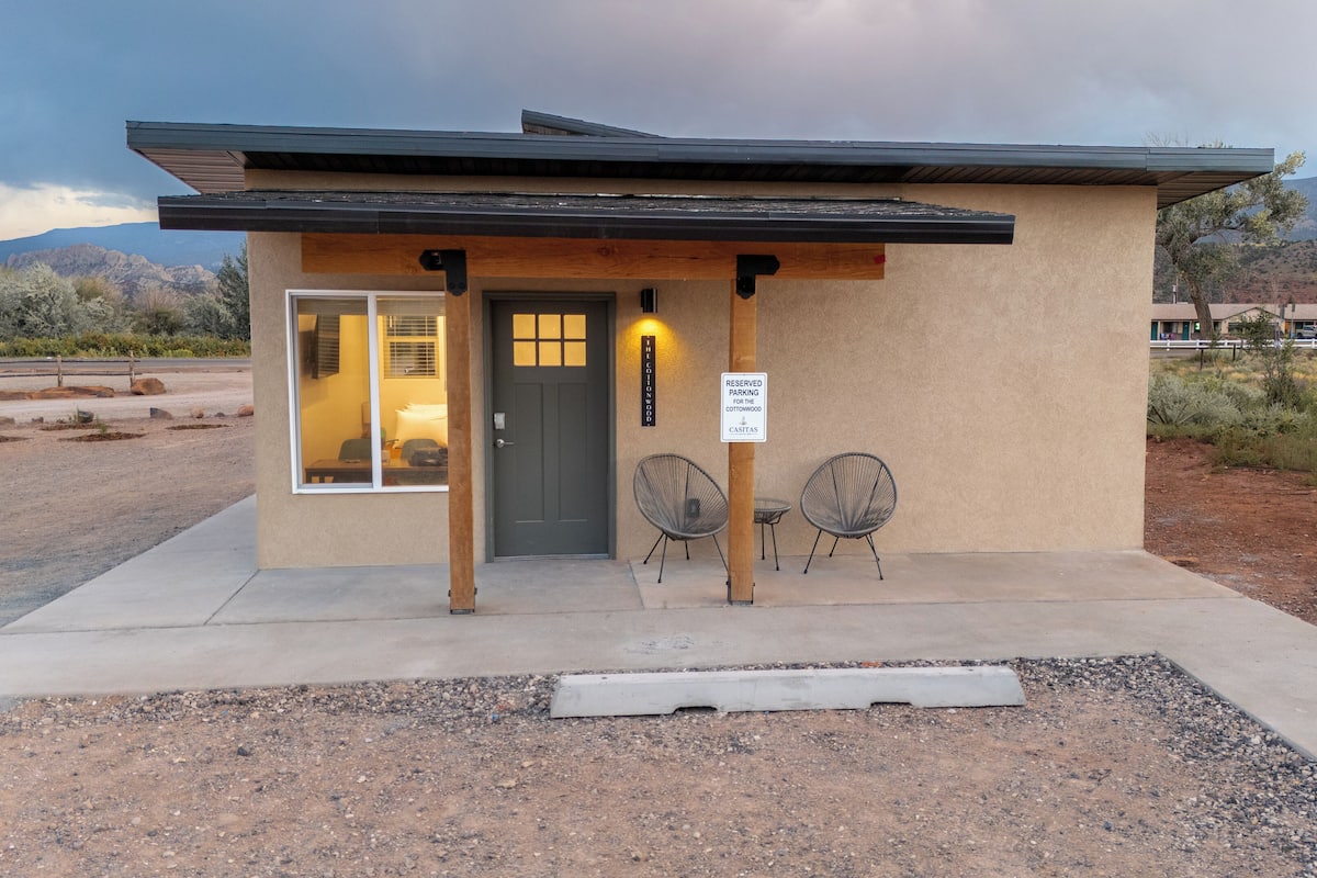 A small building with a door, two chairs outside, and a sign indicating reserved parking.
