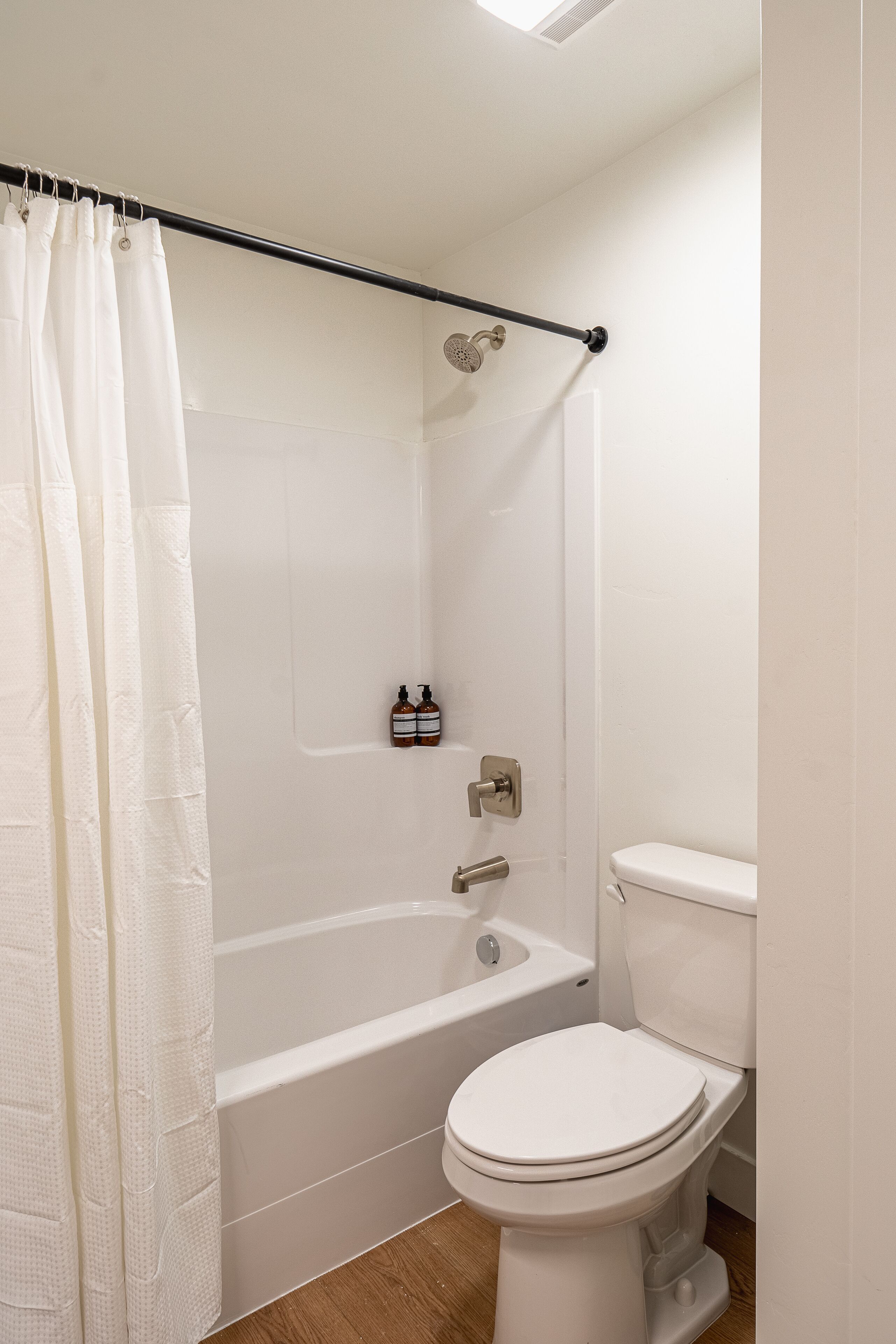 A bathroom with a bathtub, toilet, and a shower curtain.