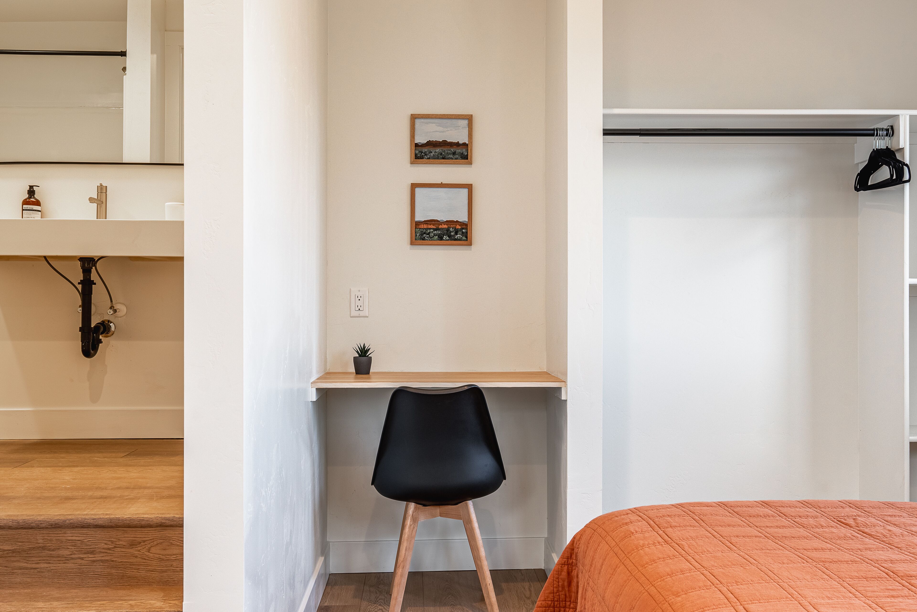 Ein Schlafzimmer mit einem Bett, einem Schreibtisch, einem Stuhl, einem Kleiderschrank und zwei gerahmten Bildern an der Wand.