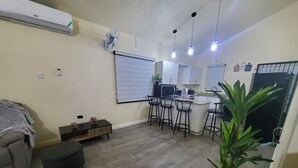 Un espacio habitable compacto con kitchenette, comedor y zona de estar.