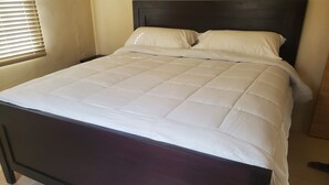 Una cama con cabecera oscura y ropa de cama blanca.