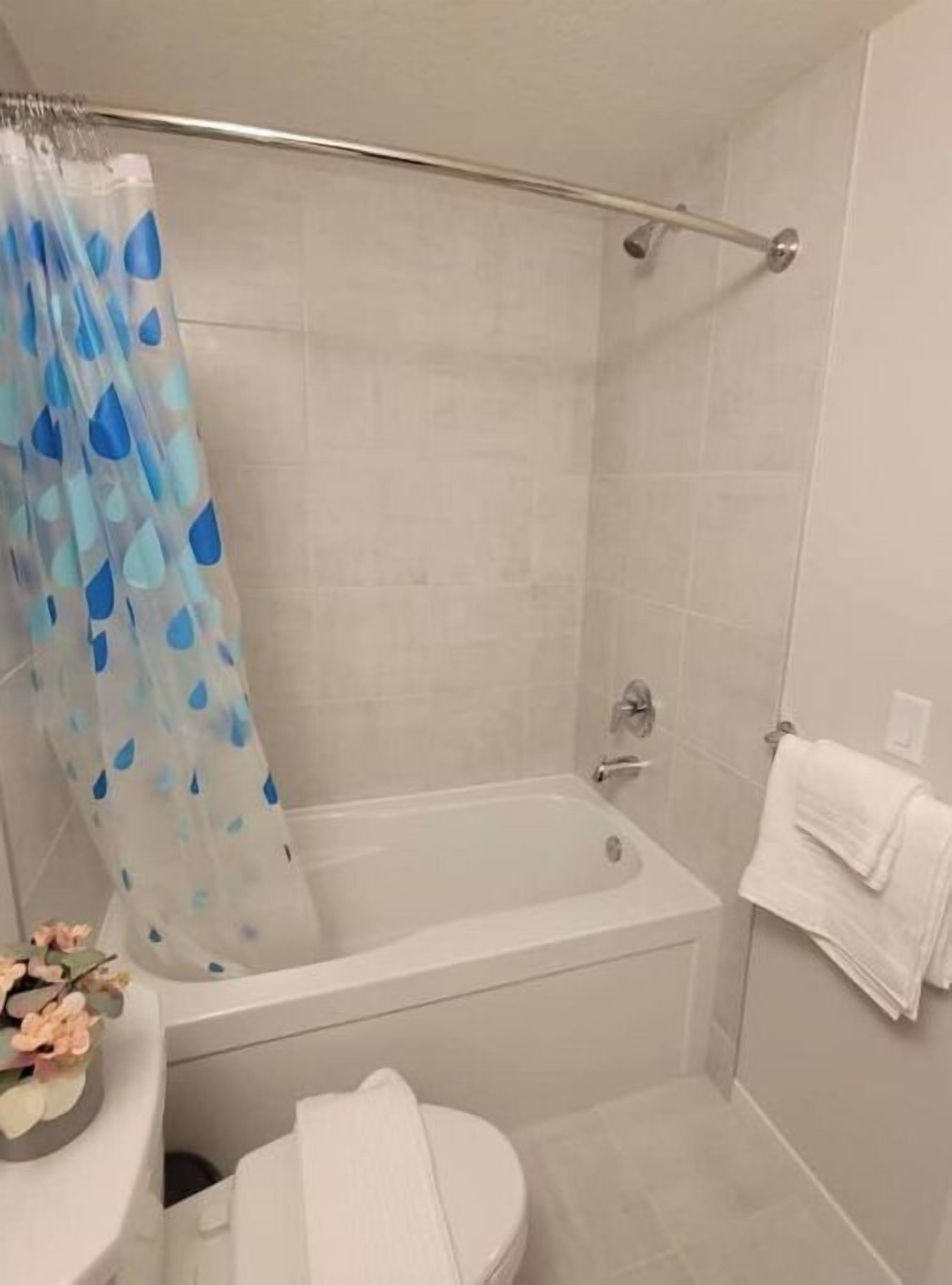 A bathroom with a bathtub, toilet, and shower curtain.