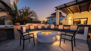 An outdoor seating area with a circular fire pit, cushioned seating, and a pergola overhead. - Casa Alas. Newly built, private pool, and a short walk to the beach! (Todos Santos)