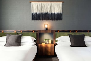 Ein Hotelzimmer mit zwei Betten, einer Wandleuchte und einem kleinen Tisch mit einer Vase.