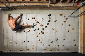 Eine Person klettert an einer Holzwand mit vielen Griffen.