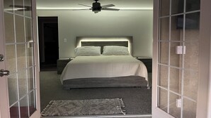 A bedroom with a bed, a ceiling fan, and a nightstand.